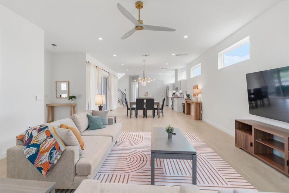 The home opens up into one airy space where living, dining, and kitchen flow together. A neutral palette, playful pops of color, and a sleek sculptural fan keep things bright and welcoming, ideal for gathering, hosting, or simply spreading out.