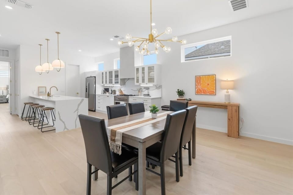 Settle in for shared meals and  conversation. The handsome dining table seats six beneath a striking statement chandelier, with a cheerful citrus art piece adding warmth. The perfect setting for everything from morning coffee to celebratory dinners.