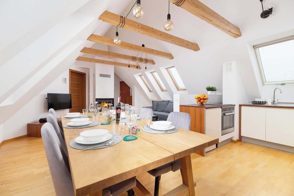 Open-plan space combining the dining area, living room, and kitchenette under high vaulted ceilings with exposed wooden beams.
