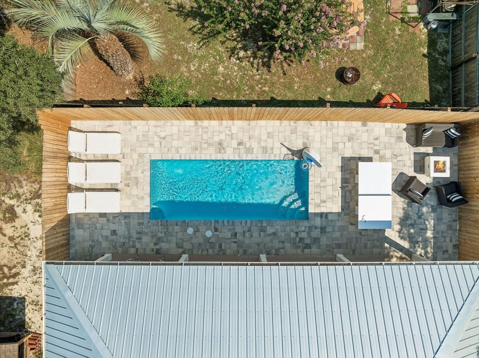 Private pool oasis with loungers, patio seating, and tropical privacy