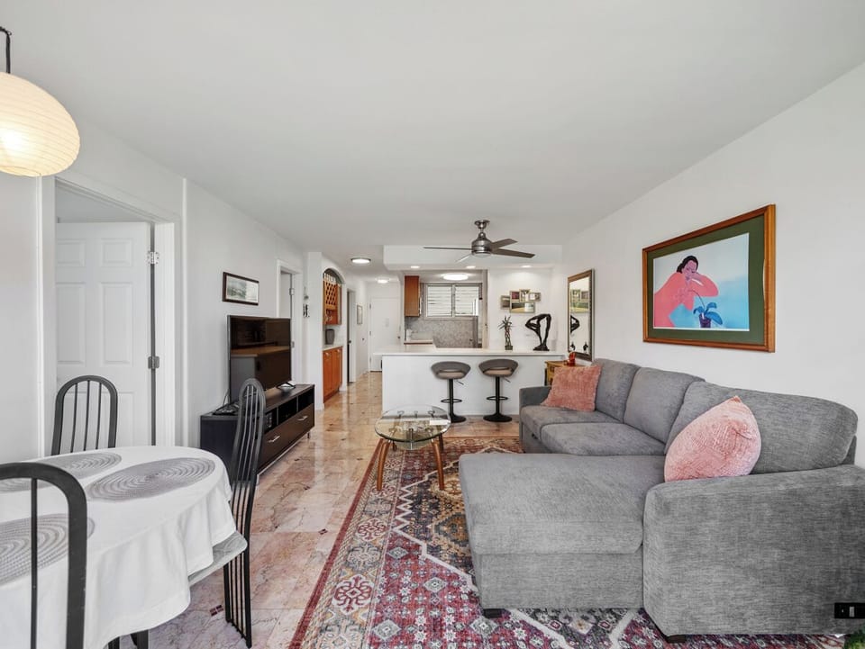Living Room - Stretch out in the open living and dining space, where a queen-size sofa sleeper, Smart TV, breakfast bar, and full kitchen provide flexible room for daily life during a monthly Honolulu visit.