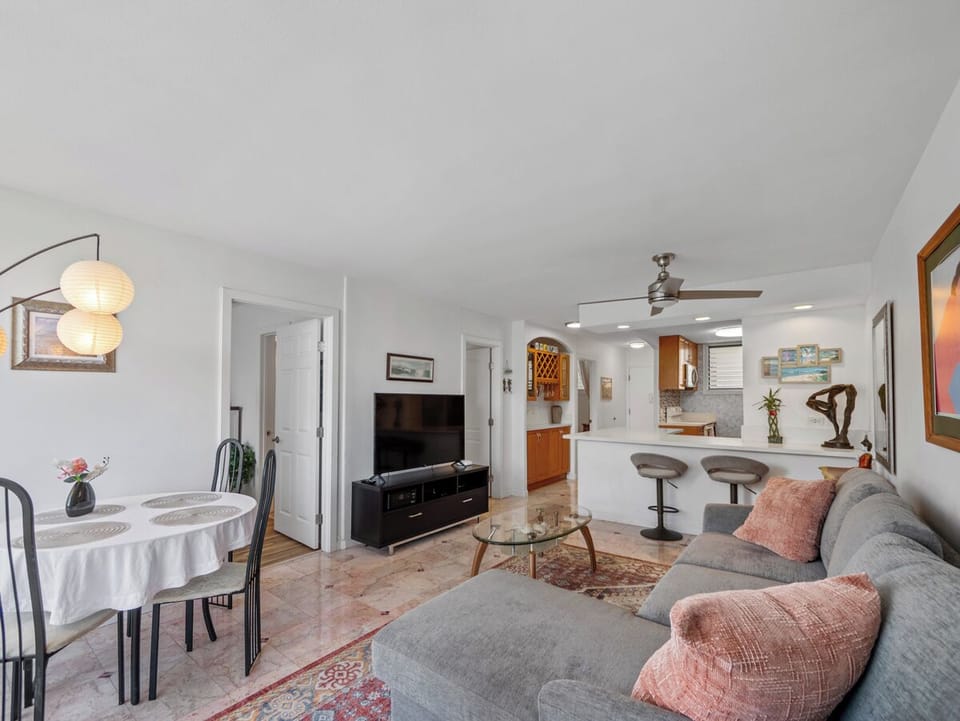 Living Room - Share meals, stream a favorite show, or ease into a quiet evening in this comfortable open-plan living area, with dining, kitchen seating, and space to gather during an extended Waikiki stay.