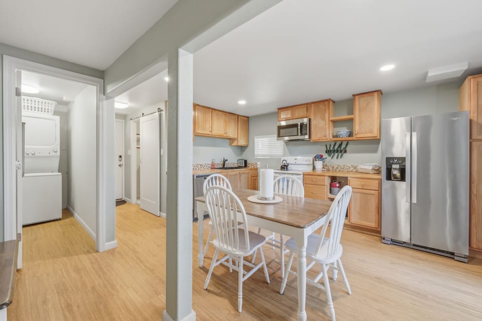 Your fully equipped kitchen features warm wood cabinetry, stainless steel appliances, and a cozy dining table perfect for home-cooked meals and morning coffee together.