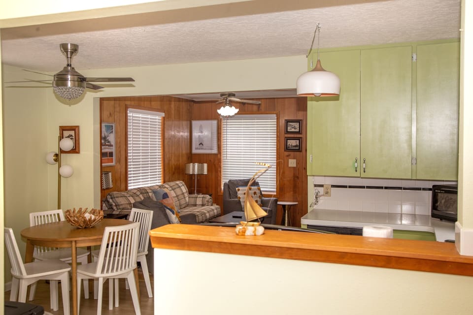 Step into your open-concept living space where the kitchen, dining, and lounge areas flow together. Enjoy home-cooked meals at the wooden table, relax on the cozy plaid sofas, and make yourself at home.
