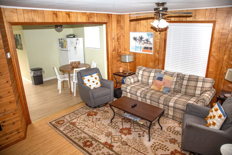Settle into this cozy living room, where warm wood paneling and comfortable seating invite you to relax after your adventures, with natural light streaming through large windows.