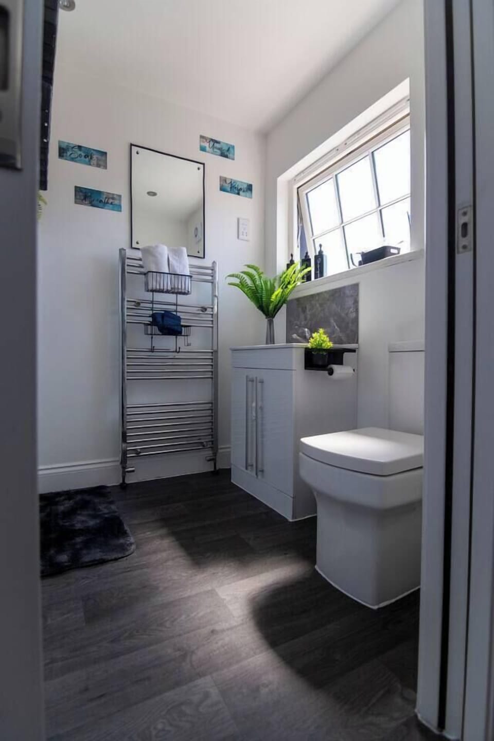 Bright modern bathroom with natural light, stylish finishes, and heated towel rack