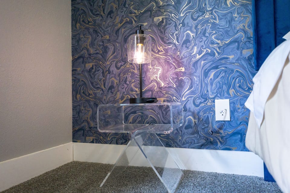 Modern bedside setup with bold blue accent wall and sleek acrylic table