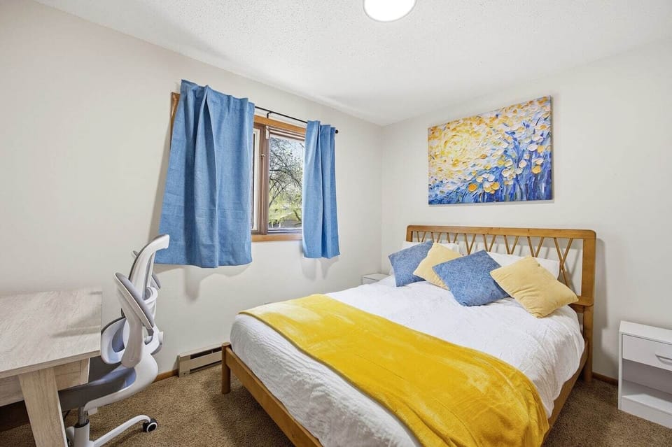 Queen bed with blackout curtains and dedicated workspace.