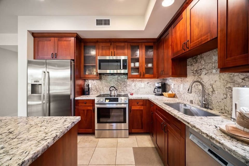 Stainless steel appliances with granite countertops & backsplash, and custom wood cabinetry