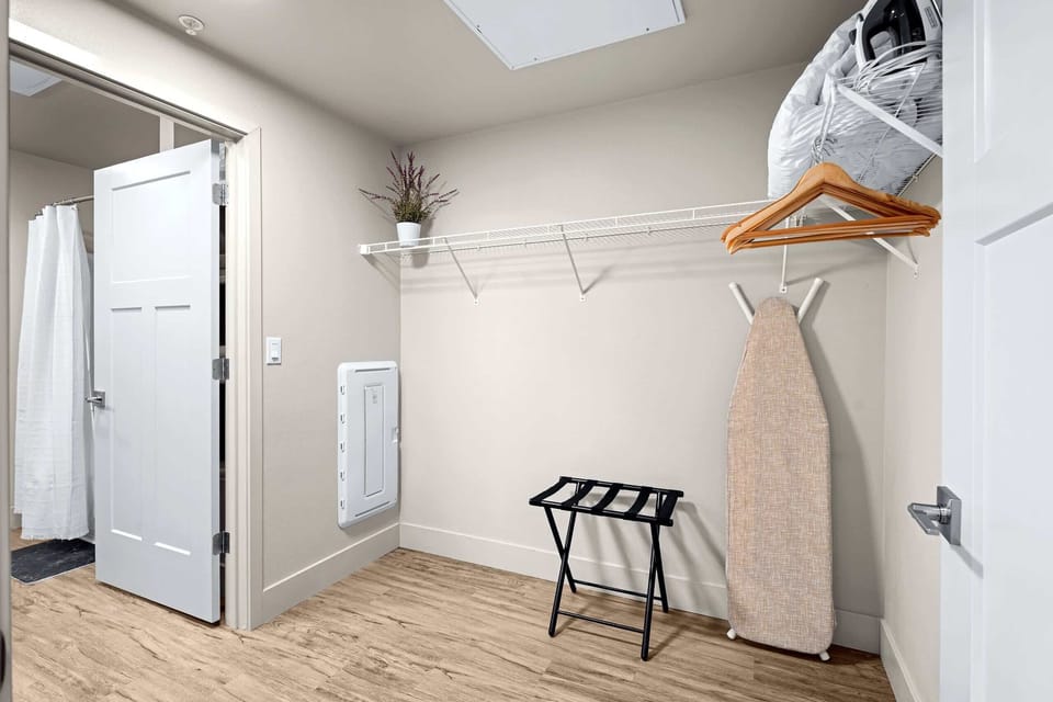 The walk-in closet includes a luggage rack, iron, and ironing board.
