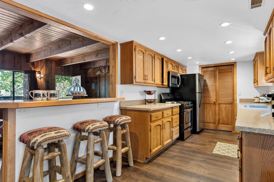 Well-appointed kitchen featuring classic wood cabinetry, breakfast bar seating, and modern stainless steel appliances.