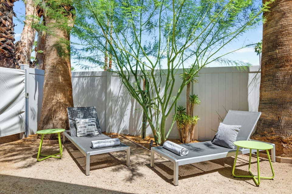Private outdoor sitting area with Adirondack chairs, desert landscaping, and direct bedroom access.