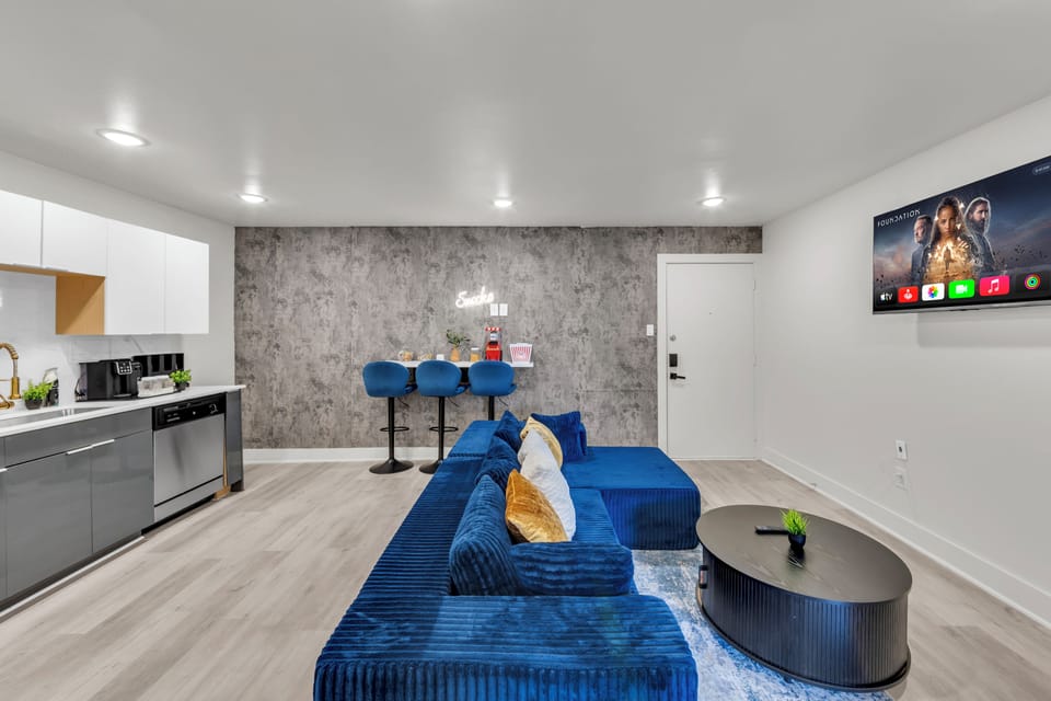 Modern open living space with plush sectional, TV, and sleek breakfast bar