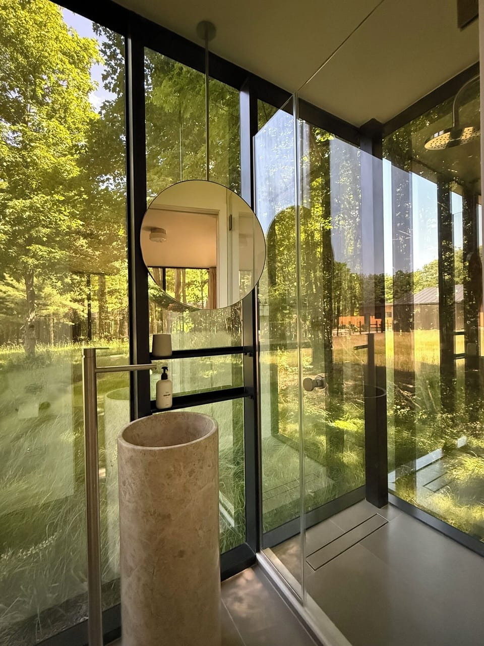 Freshen up in the glass-walled bath, where a sculptural stone basin opens right to the forest.