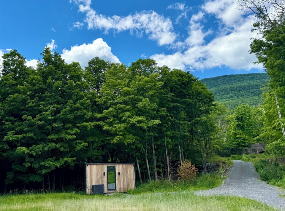 The guest house at the meadow's edge, a gravel drive winding toward the Catskills.