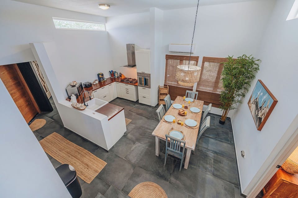 An overhead view shows the practical kitchen layout, generous counters, and dining table for six guests.