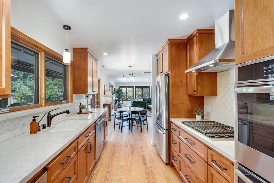Your gourmet kitchen awaits with rich wood cabinetry, modern appliances, and elegant countertops. Natural light floods the space through expansive windows, creating a warm atmosphere for cooking and gathering.