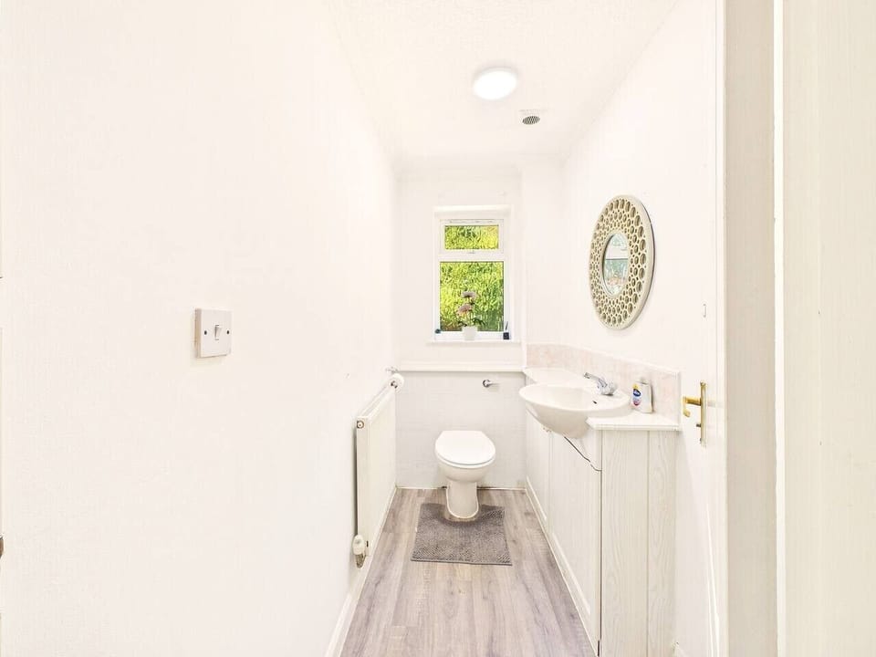 Convenient guest WC with a bright window and stylish decorative mirror.