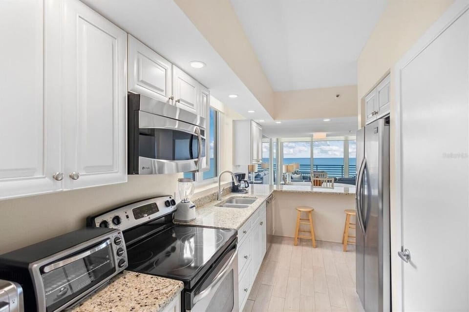 Granite countertops and stainless appliances line the galley kitchen with a view toward the ocean balcony.