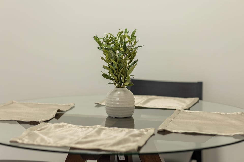 Minimalist glass dining table with stylish greenery centerpiece