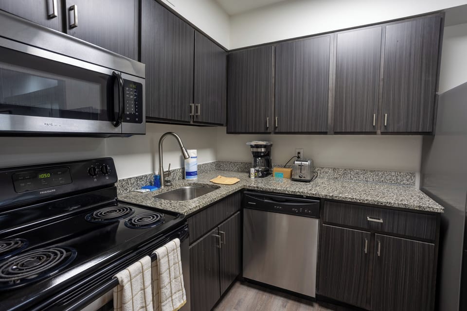 Modern kitchen with granite counters, stainless appliances, and coffee setup