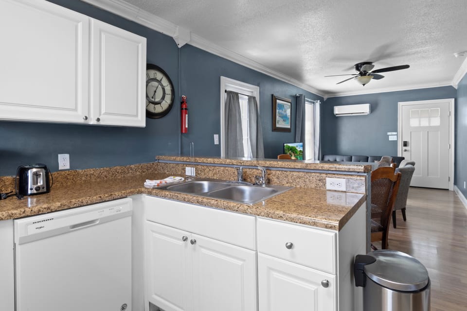 The fully equipped kitchen features white cabinetry, a dishwasher, a double sink, and a convenient breakfast bar that opens directly to the living area.