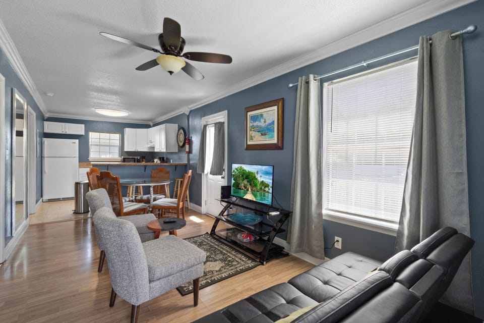 his wide view showcases the seamless, open-concept flow connecting the living area, dining table, and fully equipped kitchen.