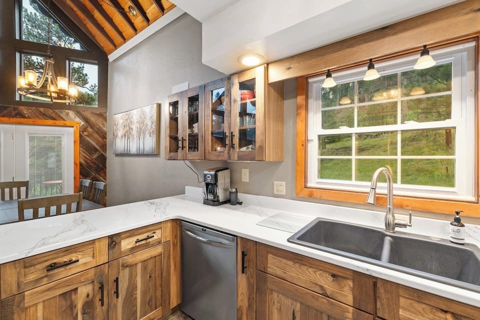 The kitchen area features a functional sink area with a window overlooking the outdoors, bringing in natural light and creating a pleasant space for preparing meals.