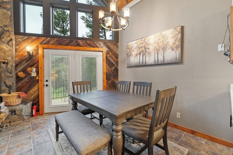 The dining area features a high ceiling and a door leading to the outdoor deck, creating a bright and inviting space that seamlessly connects indoor dining with the beauty of the outdoors.