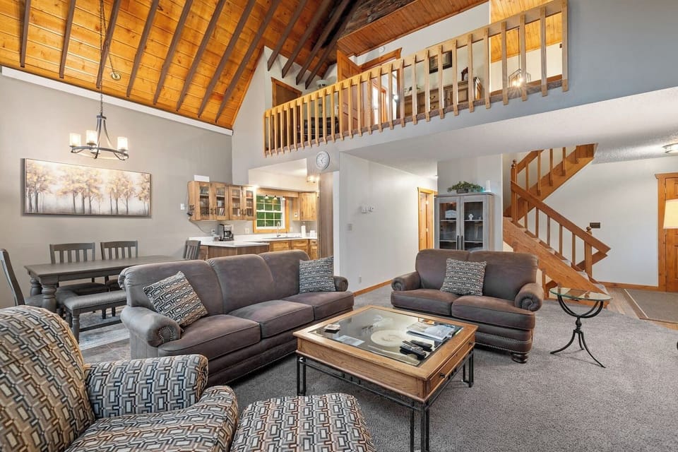 The open-concept living and dining area features a spacious layout with a cozy loft-style upper level overlooking the main space, creating a warm and inviting atmosphere for gathering and relaxation.