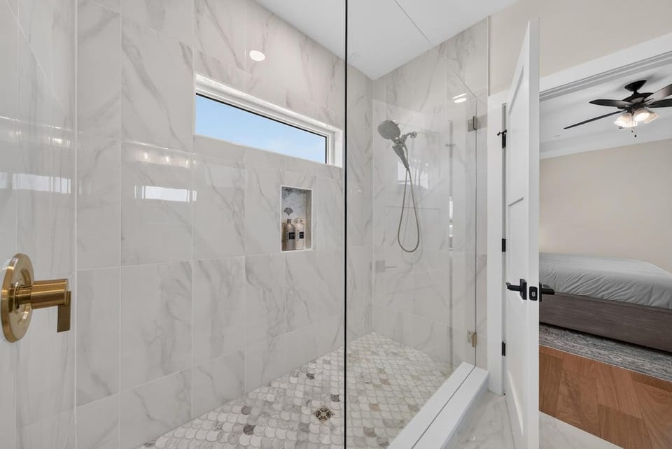 Walk-in and say awhile in this incredible master shower, featuring a patterned stone floor and tons of natural light.