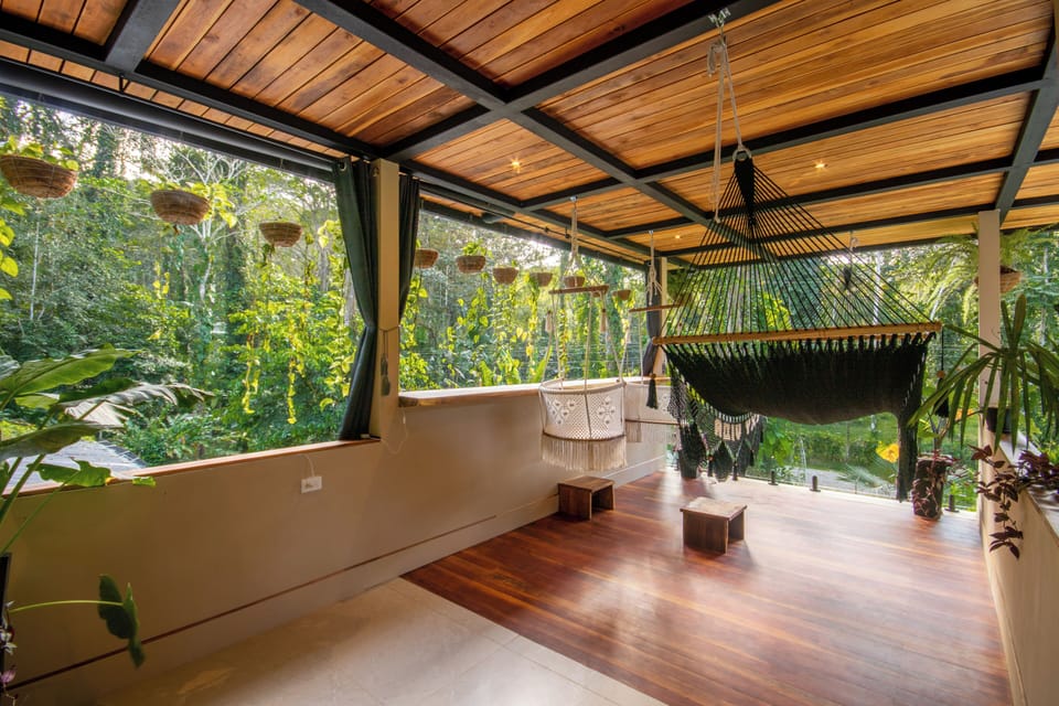 Upper lounge with double hammock, hanging chairs and rainforest views.