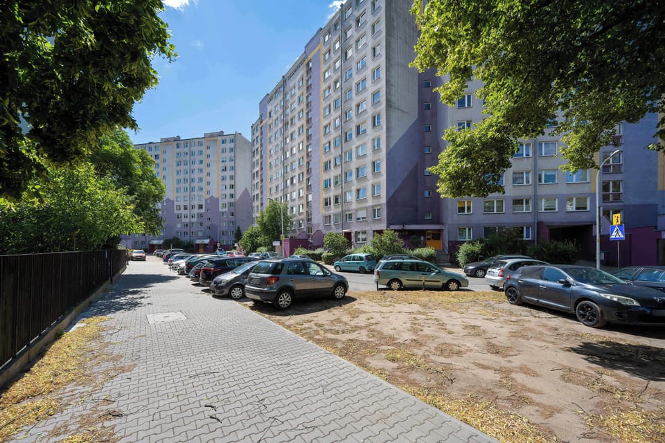 Exterior view of the apartment building with trees, and a pedestrian walkway.