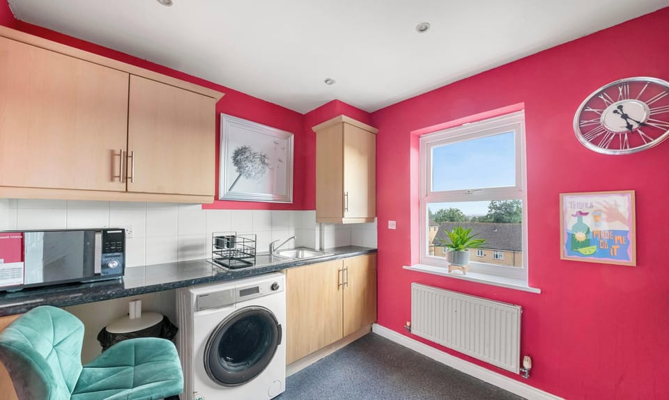 This kitchen features red walls, wooden cabinets, a built-in oven with a gas stove, a kitchen sink, and a front-loading washing machine.