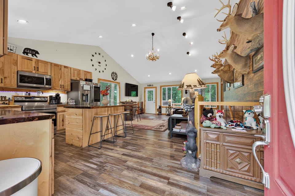 An open-concept living space and kitchen with wood flooring, rustic cabinetry.