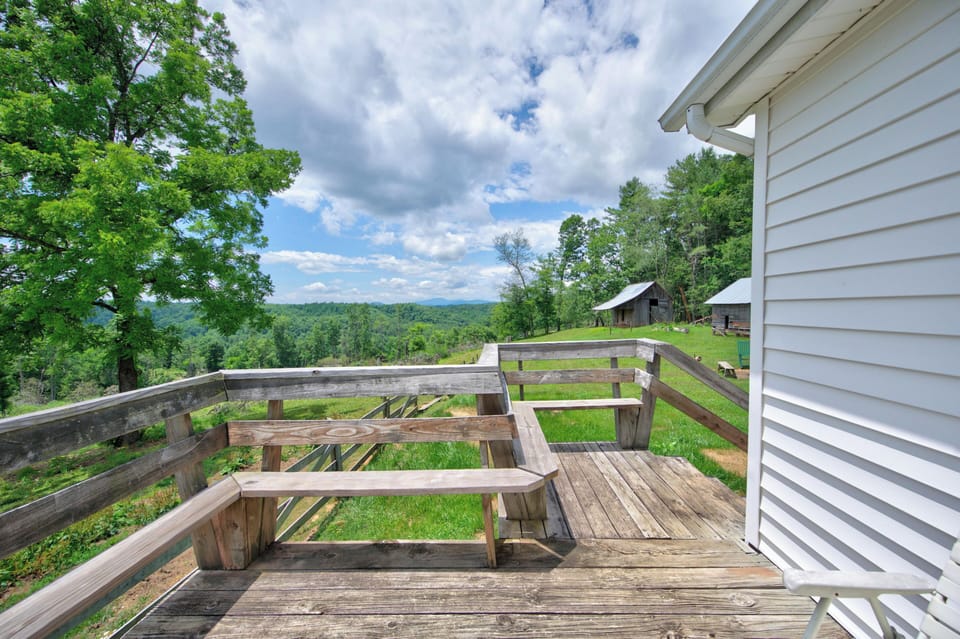 An outdoor wooden deck with built-in seating overlooking a scenic green landscape.