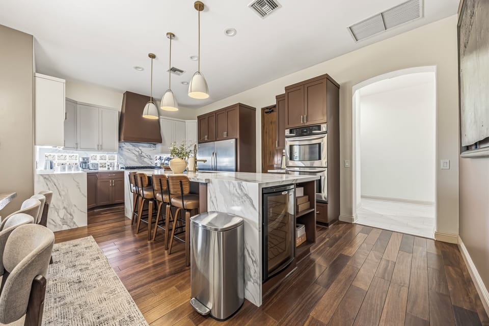 Modern chef’s kitchen: waterfall island, double ovens, wine fridge & seating
