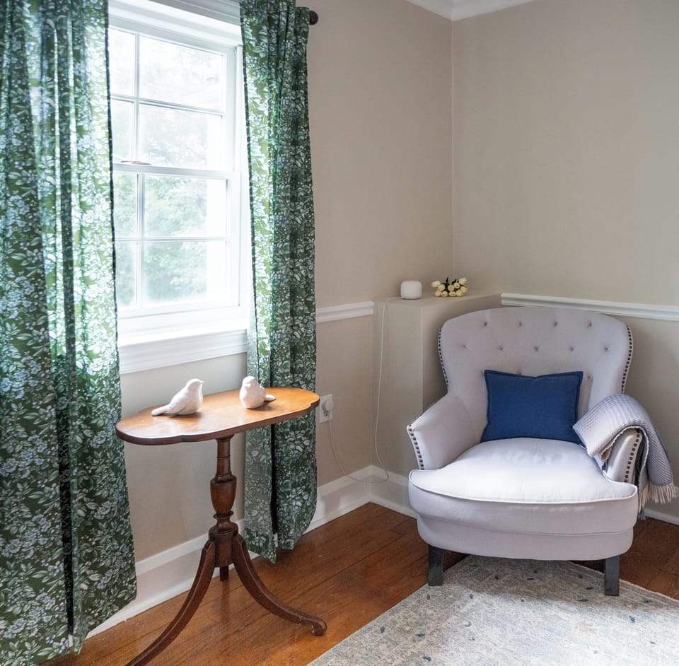 Tufted reading chair and luggage rack in the back bedroom