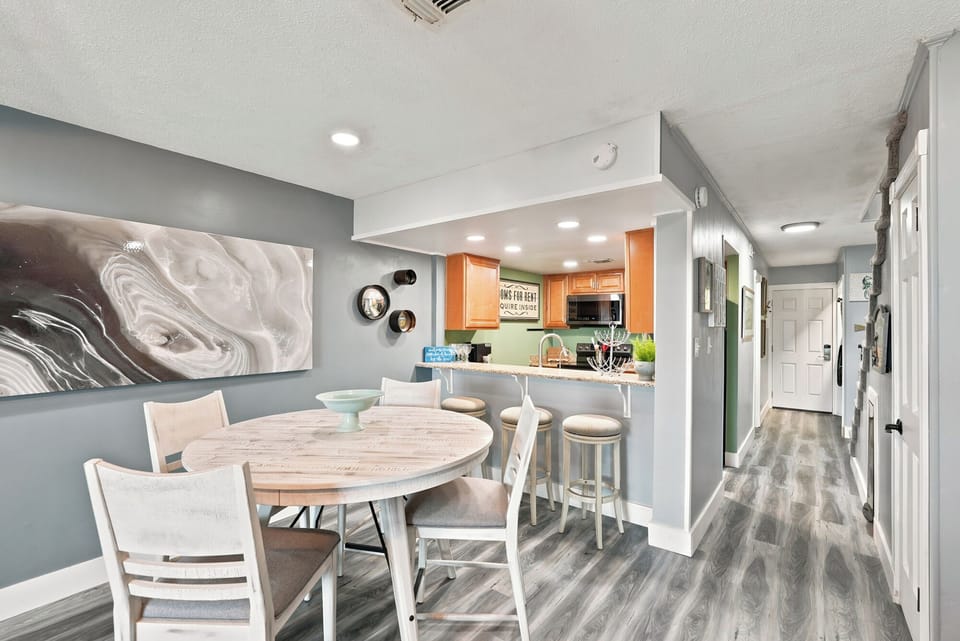 Picture yourself sharing meals at this stylish dining table, with the open kitchen just steps away. The modern décor and warm lighting create a welcoming space where your group can gather and relax together.