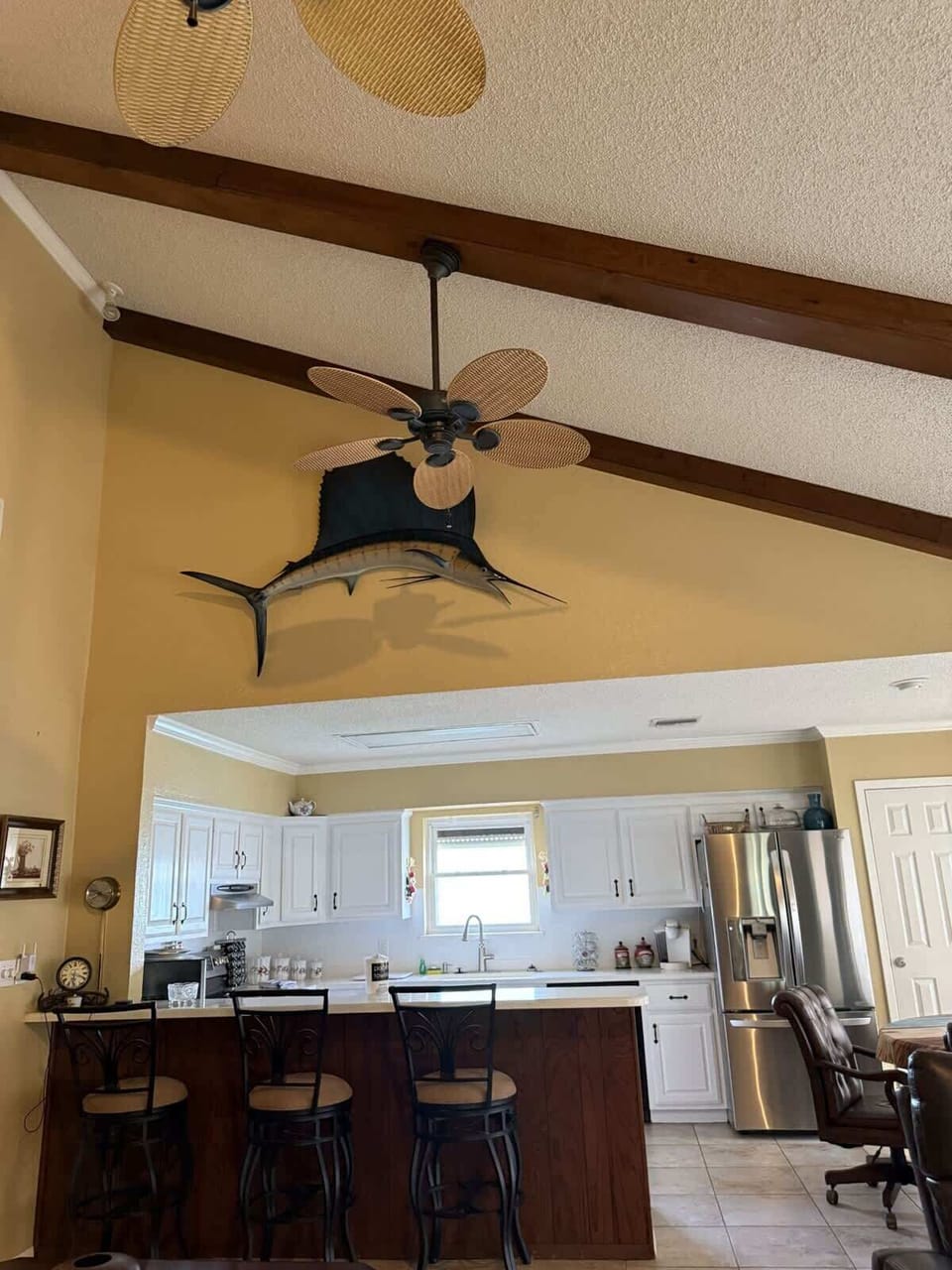 Kitchen area with counter seating, ideal for casual dining and social cooking, with a decorative swordfish display above