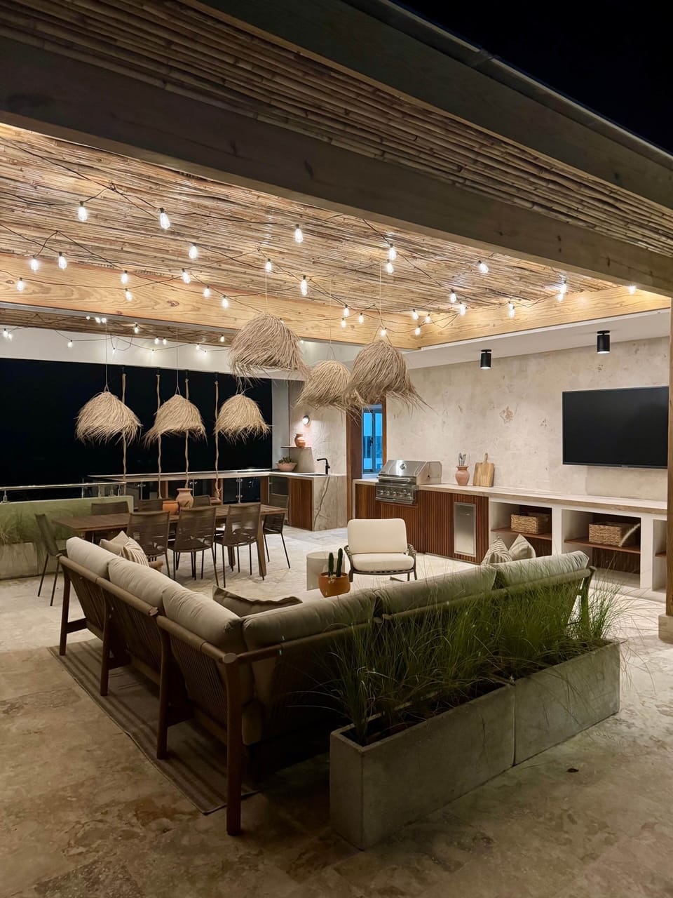 After dark the rooftop glows: string lights, lounge seating, TV under the stars