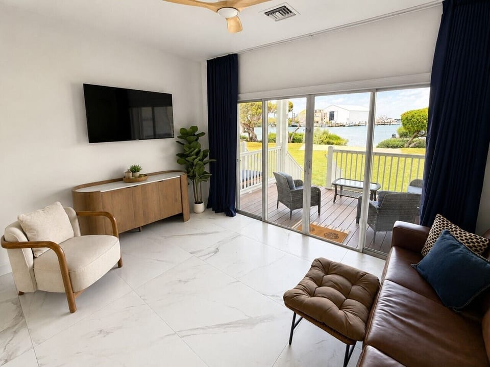 Bright waterfront living room with Smart TV, comfortable seating, and sliding doors leading to the covered patio.