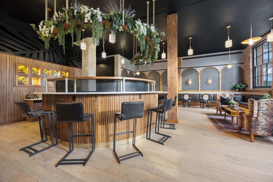 The lobby lounge offers additional seating and gathering spaces surrounded by rich wood details and greenery.