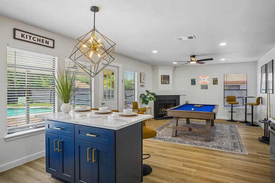 Bright open living space with pool table, fireplace, and stylish blue island