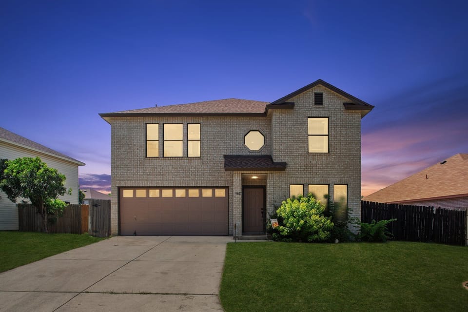 Inviting two-story brick home with garage and great curb appeal at dusk