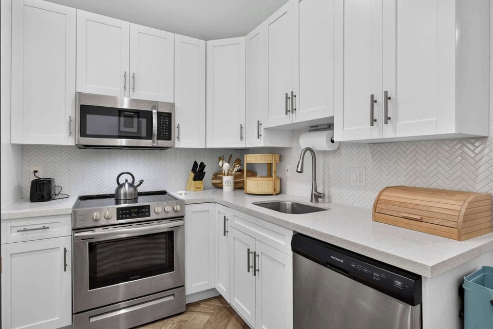 Crisp white shaker cabinetry and a stainless steel range offer plenty of counter space for preparing home-cooked meals