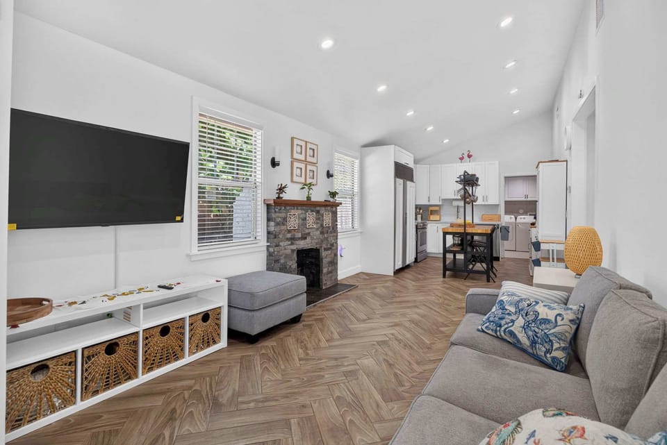 Bright living room with a mounted smart TV, comfortable sofa seating, and gorgeous herringbone wood flooring throughout