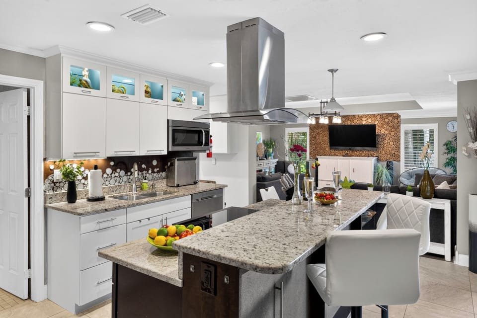 Modern kitchen with a spacious island, bar seating, and open flow into the family and living rooms.