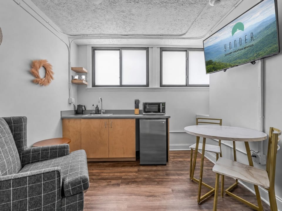 The 321-square-foot suite features a queen sleeping area, kitchenette, bistro table, seating, and smart TV.
