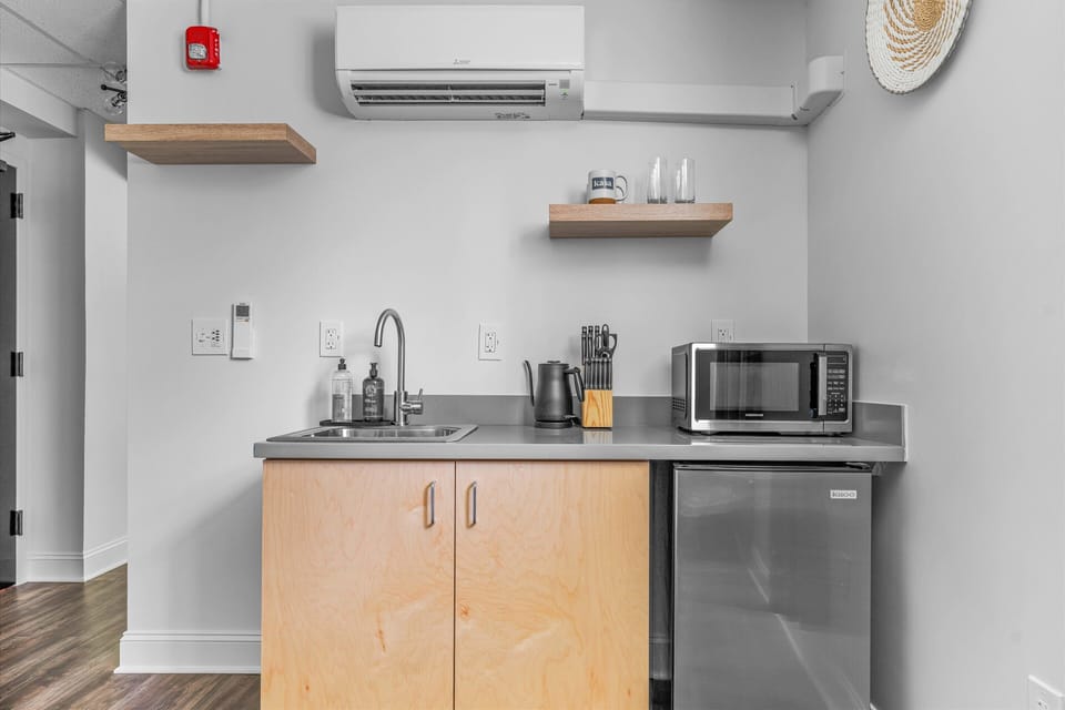 Compact private kitchenette with a sink, microwave, mini-fridge, and kettle.